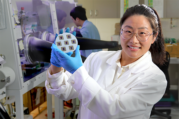 School of Engineering researcher Dr Heping Shen poses with a tandem solar cell in the PV laboratories at ANU.